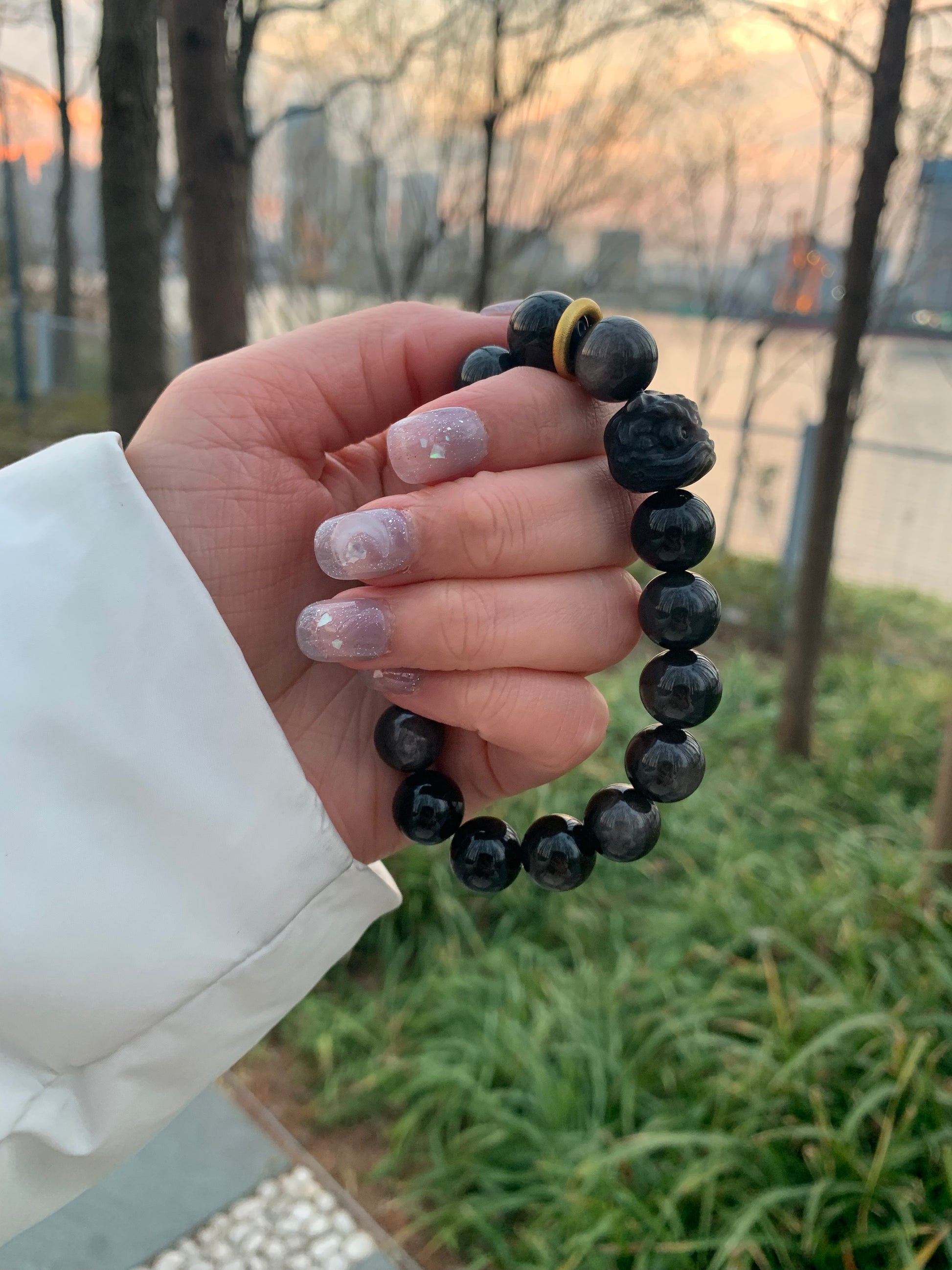 Feng Shui bracelet made of 12mm obsidian beads, adorned with a detailed lion carving and gold accents.